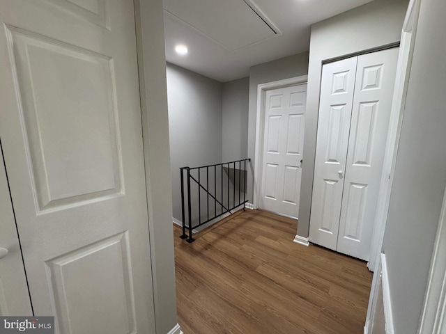 hall with baseboards, an upstairs landing, wood finished floors, and attic access