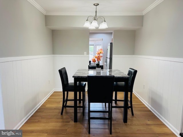 dining room featuring crown molding, wood finished floors, and a wainscoted wall