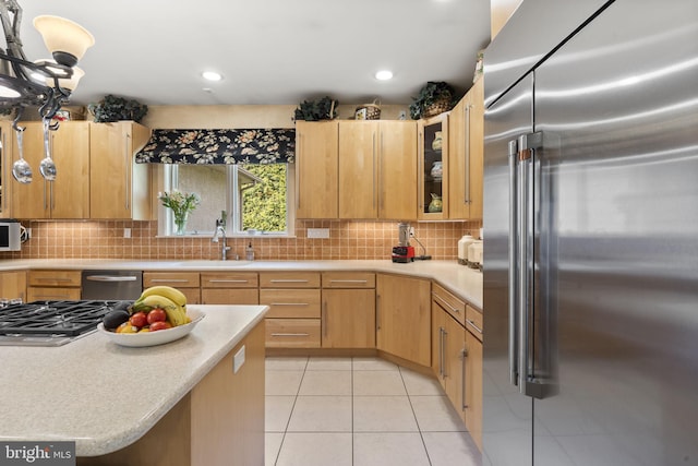 kitchen with light tile patterned floors, light countertops, backsplash, stainless steel appliances, and a sink