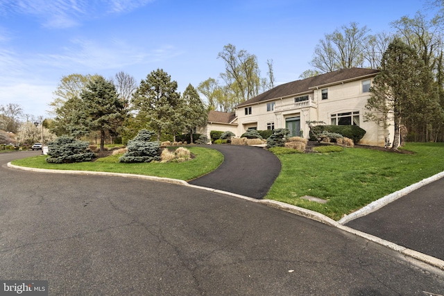 view of front of house with a garage, aphalt driveway, stucco siding, and a front yard