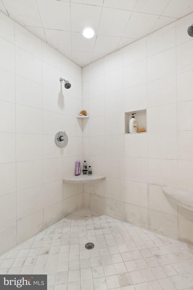 bathroom featuring tiled shower and tile patterned flooring