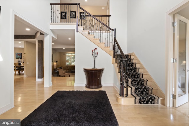 foyer entrance featuring wood finished floors, a towering ceiling, and stairway