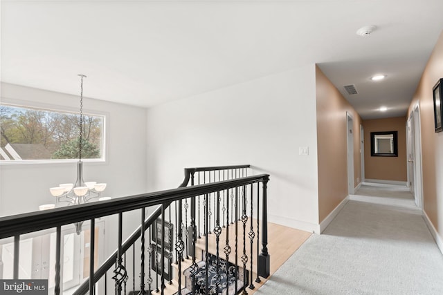 corridor with a chandelier, an upstairs landing, baseboards, and visible vents