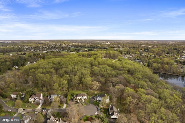drone / aerial view featuring a wooded view and a water view