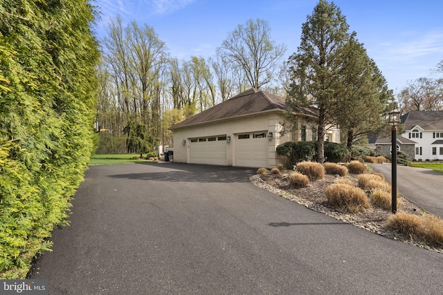 view of home's exterior with an attached garage, stucco siding, and aphalt driveway