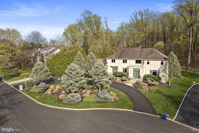 view of front of home featuring aphalt driveway, stucco siding, and a front lawn