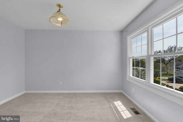 spare room featuring baseboards, visible vents, and light colored carpet