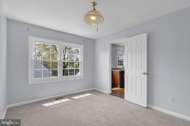 unfurnished room featuring plenty of natural light, baseboards, visible vents, and carpet floors