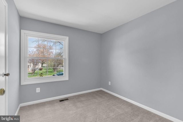carpeted spare room with visible vents and baseboards
