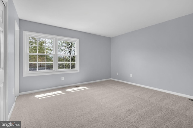 carpeted empty room featuring visible vents and baseboards
