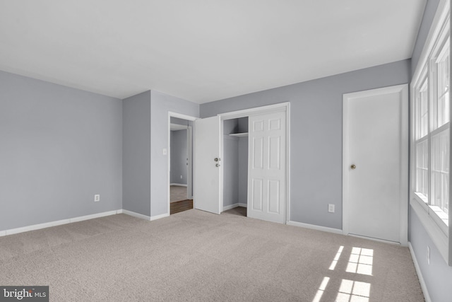 unfurnished bedroom with baseboards, a closet, multiple windows, and carpet
