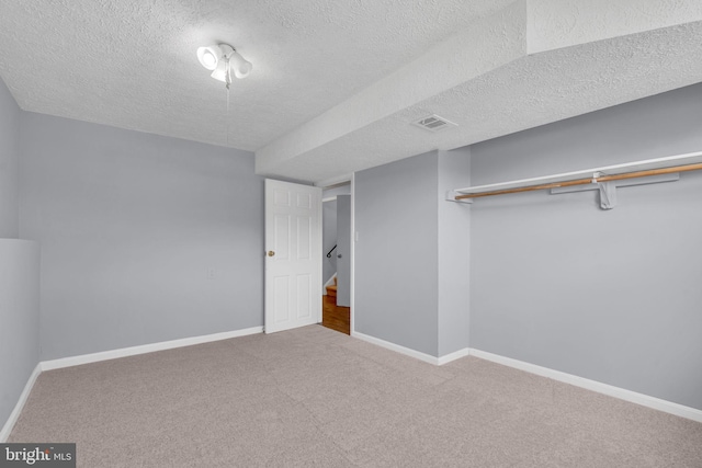 unfurnished bedroom featuring baseboards, carpet flooring, a textured ceiling, and visible vents