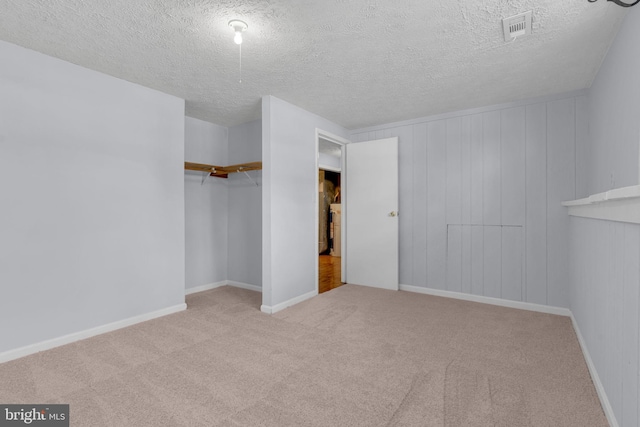 interior space with a textured ceiling, a closet, carpet floors, baseboards, and visible vents