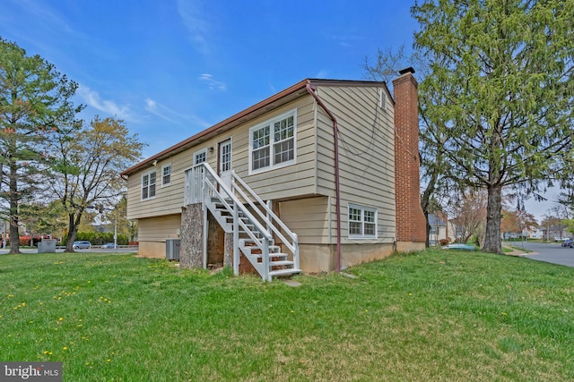 rear view of property featuring a chimney, central AC unit, stairway, and a lawn