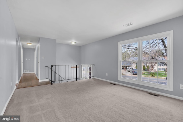 empty room with baseboards, visible vents, and carpet flooring