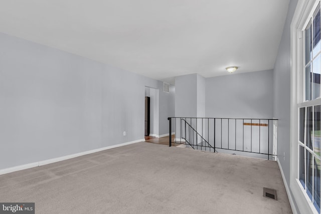 carpeted spare room featuring visible vents and baseboards