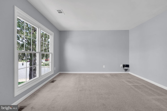 unfurnished room with baseboards, visible vents, and carpet