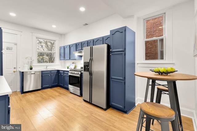 3218 13th St NW, Washington, DC 20010 - kitchen featuring blue cabinets, light wood-style floors, stainless steel appliances, light countertops, and under cabinet range hood