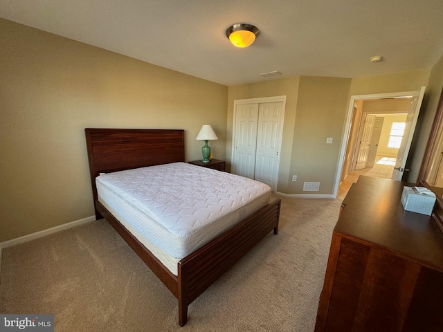 bedroom featuring a closet, light colored carpet, baseboards, and visible vents