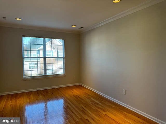 spare room with crown molding, baseboards, and wood finished floors