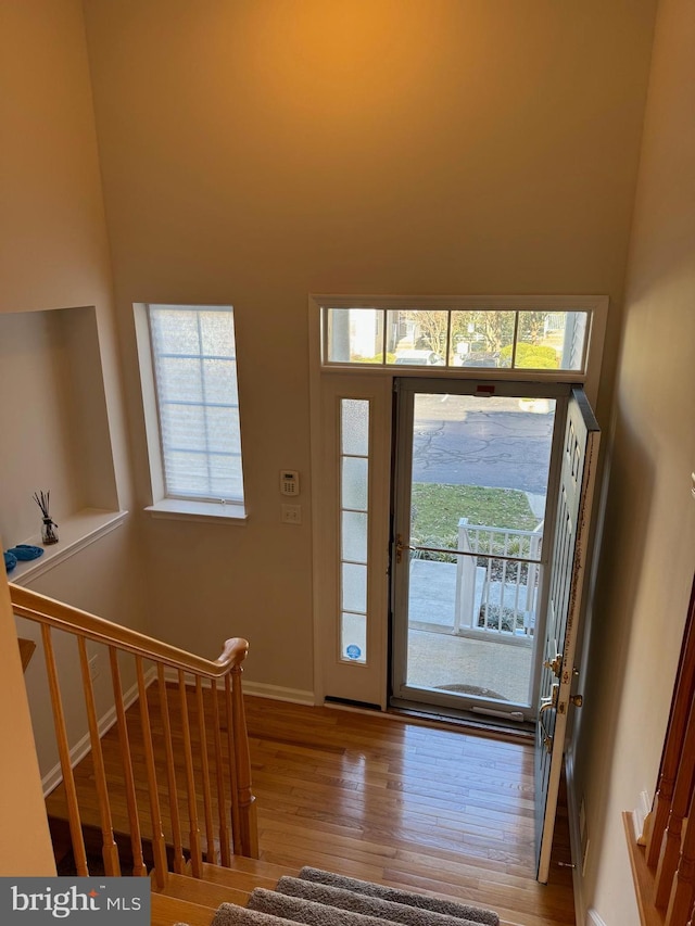 foyer with wood finished floors, baseboards, stairs, and a wealth of natural light
