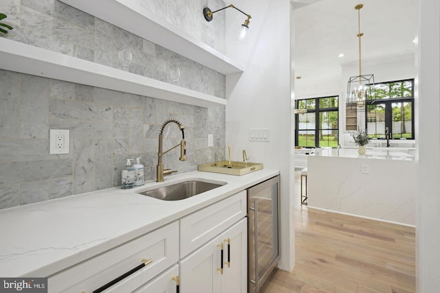 9210 Marseille Dr, Potomac, MD 20854 - indoor wet bar featuring wine cooler, decorative backsplash, light wood-type flooring, and decorative light fixtures