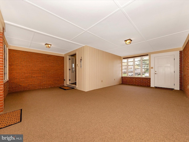 unfurnished living room with carpet and brick wall