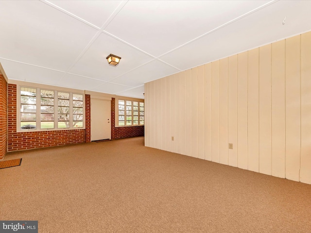 unfurnished living room with brick wall and carpet
