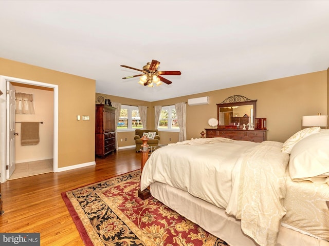 bedroom with an AC wall unit, baseboards, a ceiling fan, and wood finished floors