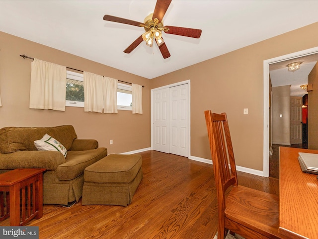 living room featuring baseboards, a ceiling fan, and wood finished floors