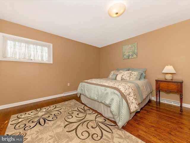 bedroom with baseboards, a baseboard heating unit, and wood finished floors