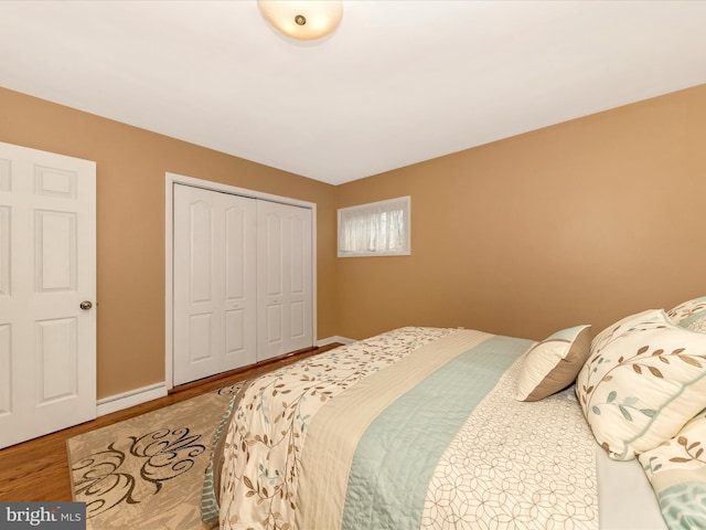 bedroom featuring wood finished floors, a closet, and baseboards