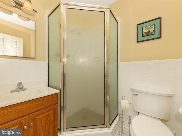 bathroom with a shower stall, toilet, a wainscoted wall, and tile walls