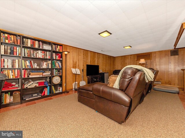 carpeted living area with wood walls and a baseboard heating unit