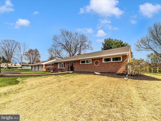 ranch-style house with a garage, a front yard, driveway, and brick siding
