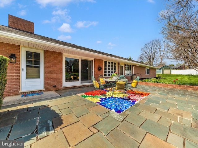 rear view of property with a patio, a chimney, and brick siding