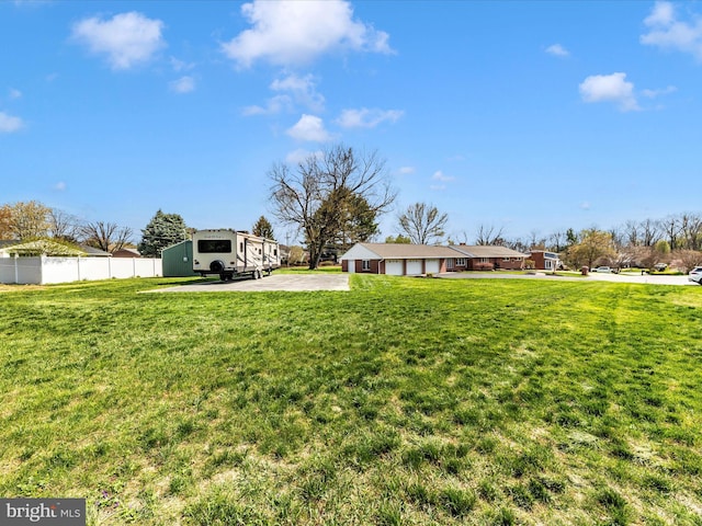 view of yard with driveway, fence, and an attached garage