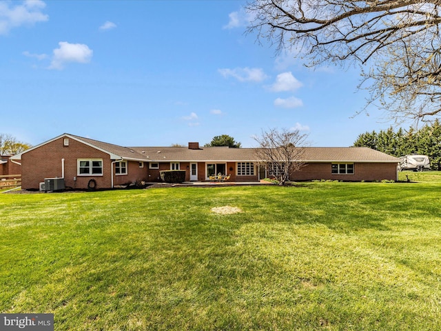 back of house with a yard, brick siding, cooling unit, and a chimney