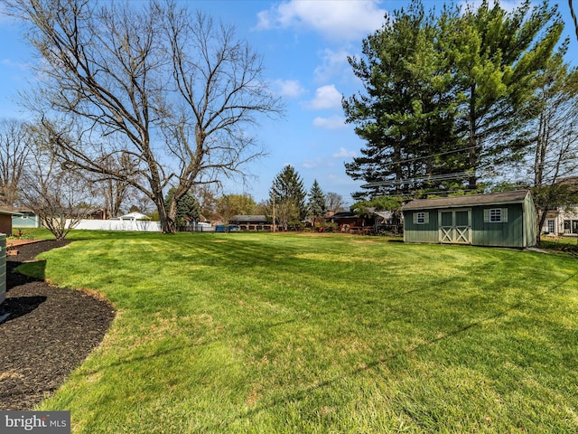 view of yard featuring an outbuilding, a shed, and fence