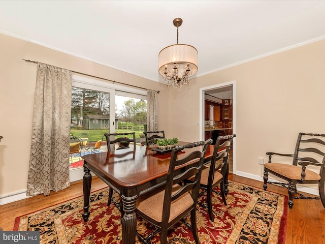 dining space featuring wood finished floors, an inviting chandelier, and ornamental molding