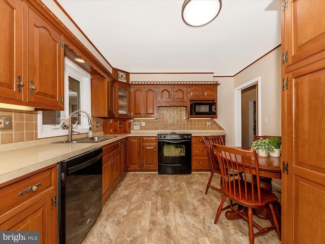 kitchen with tasteful backsplash, light countertops, black appliances, brown cabinetry, and a sink