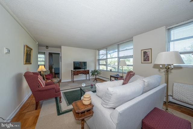 living area with a wealth of natural light, baseboards, and a textured ceiling