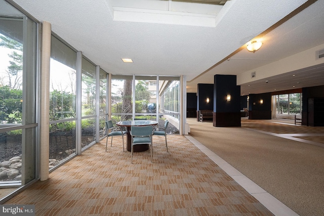 sunroom with tile patterned floors, visible vents, a wall of windows, and plenty of natural light