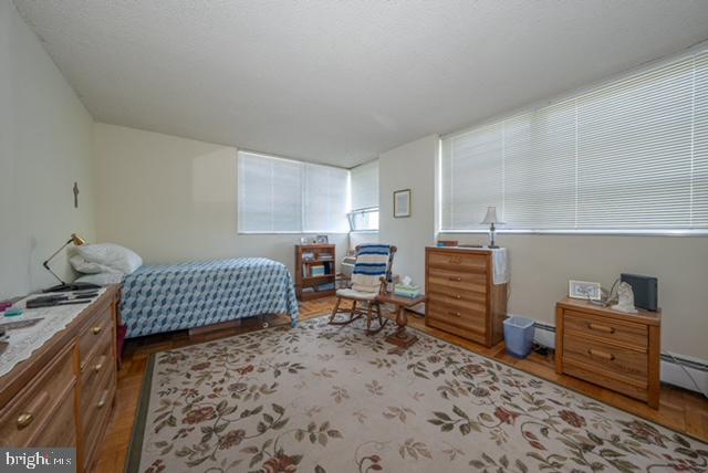 bedroom with wood finished floors and a baseboard radiator