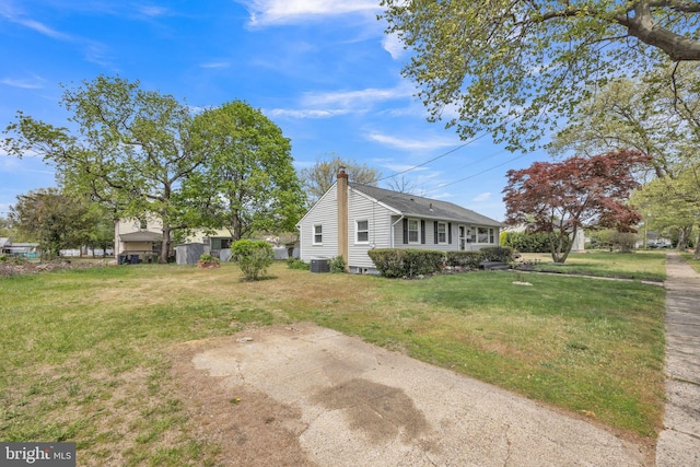view of home's exterior featuring a lawn, central AC, and a chimney