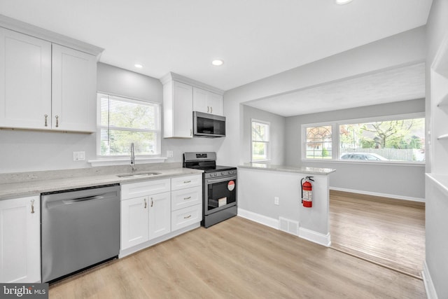 kitchen with light wood-type flooring, a sink, stainless steel appliances, and visible vents