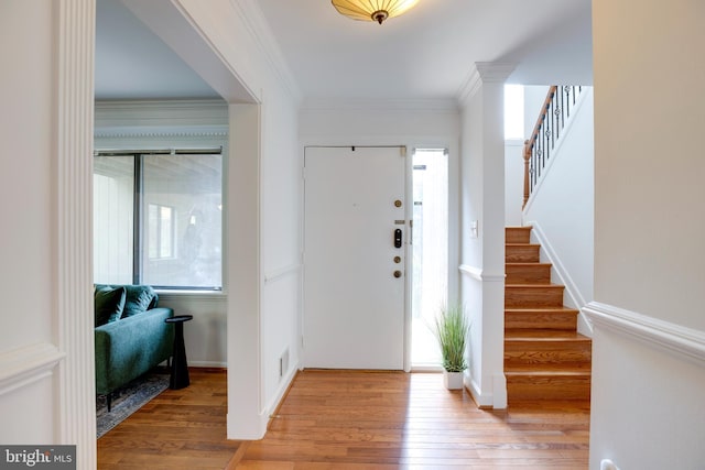 entrance foyer featuring ornamental molding, light wood-style floors, and stairs