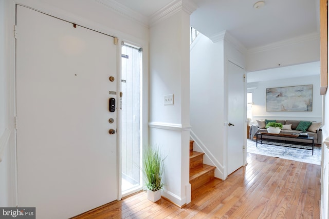 entrance foyer with stairway, light wood-style floors, baseboards, and ornamental molding