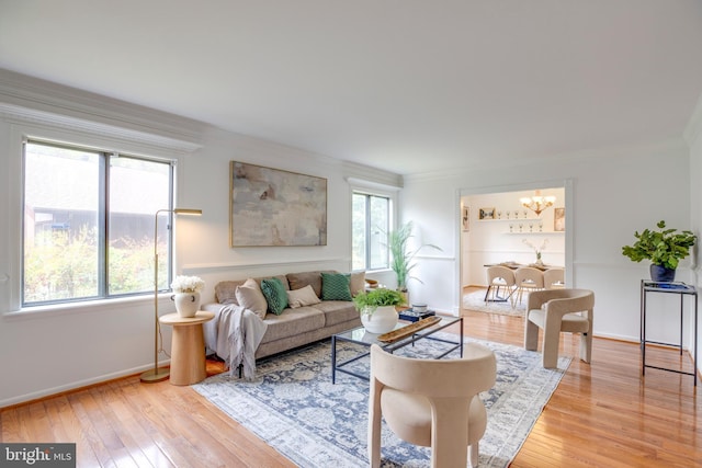 living area with an inviting chandelier, wood-type flooring, baseboards, and crown molding