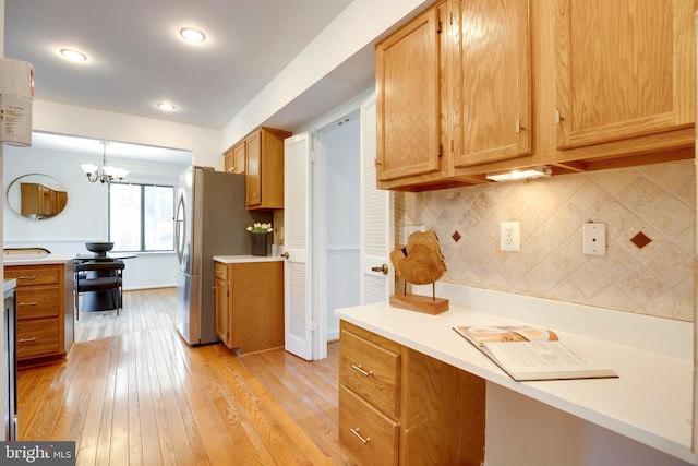 kitchen with light wood finished floors, light countertops, freestanding refrigerator, and backsplash